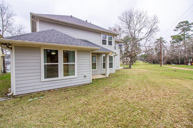 rear view of house featuring roof with shingles and a yard