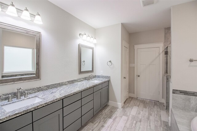 full bath with double vanity, visible vents, a sink, and wood finished floors