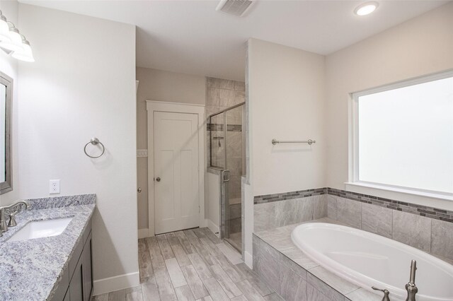 full bath featuring visible vents, baseboards, a garden tub, vanity, and a shower stall