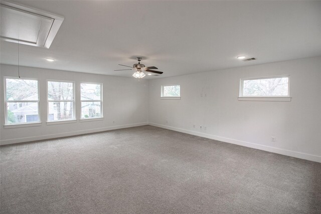 spare room featuring visible vents, a ceiling fan, baseboards, carpet, and attic access