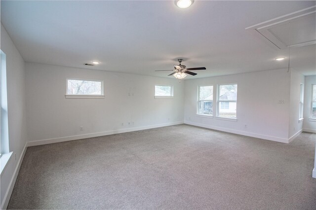 unfurnished room with ceiling fan, light carpet, visible vents, baseboards, and attic access