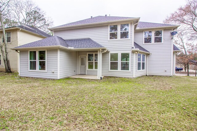 back of house with a shingled roof, a patio, and a lawn