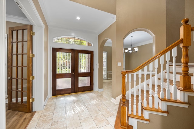 foyer with baseboards, arched walkways, stairs, crown molding, and french doors