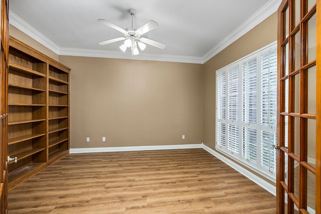 empty room featuring ornamental molding, ceiling fan, baseboards, and wood finished floors