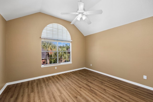 spare room featuring ceiling fan, vaulted ceiling, baseboards, and wood finished floors