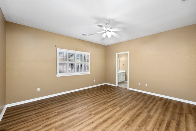 empty room with a ceiling fan, visible vents, baseboards, and wood finished floors