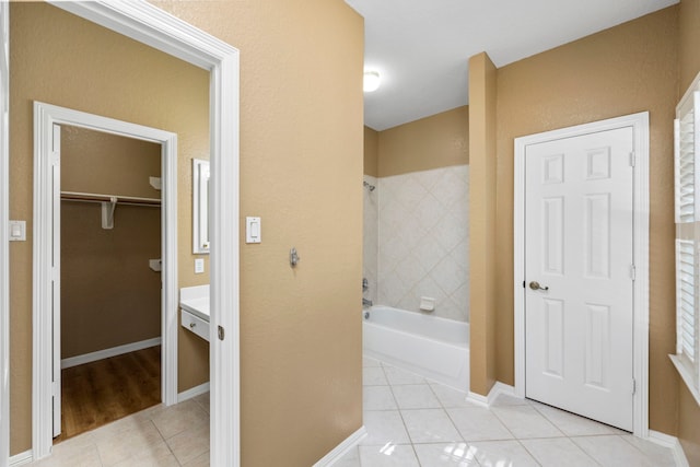 full bath featuring a spacious closet, baseboards, a bath, and tile patterned floors
