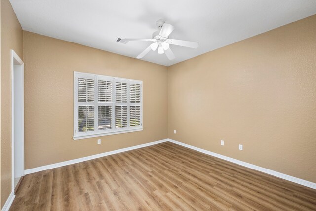 empty room with visible vents, ceiling fan, light wood-style flooring, and baseboards