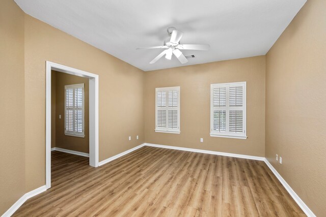 empty room featuring ceiling fan, visible vents, light wood-style flooring, and baseboards