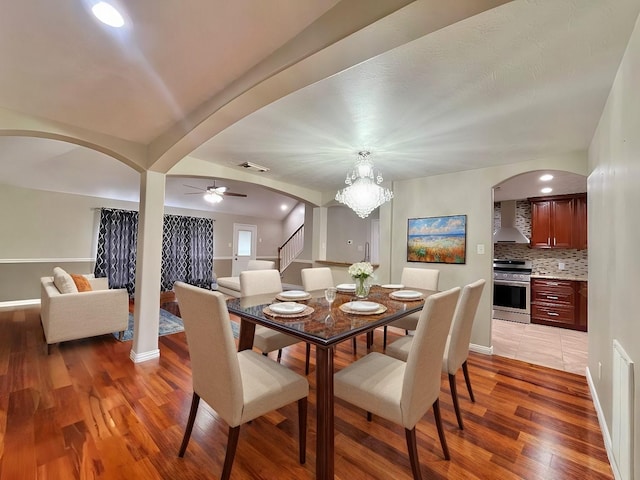 dining area with visible vents, a ceiling fan, arched walkways, light wood finished floors, and baseboards