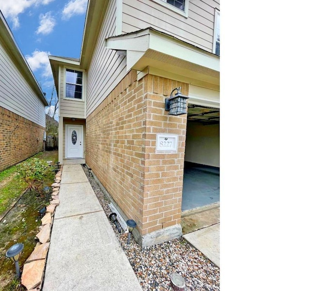 doorway to property with brick siding and a garage