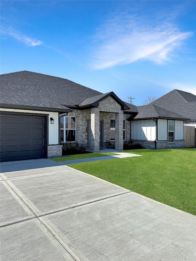 view of front facade with brick siding, roof with shingles, and a front yard