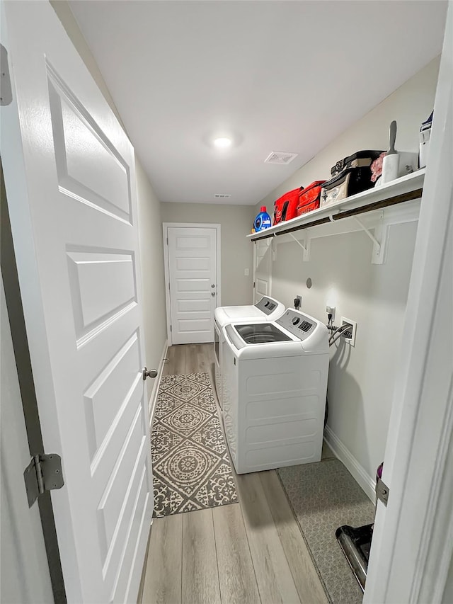 washroom featuring visible vents, light wood-style flooring, laundry area, independent washer and dryer, and baseboards