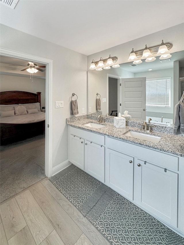 full bath featuring double vanity, a sink, baseboards, and wood finished floors