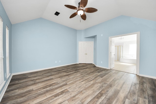 unfurnished bedroom featuring wood finished floors, a ceiling fan, baseboards, vaulted ceiling, and a closet