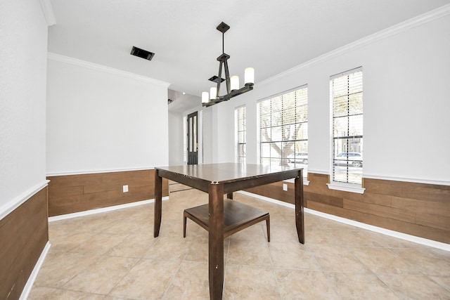 dining area with light tile patterned floors, wood walls, wainscoting, and crown molding