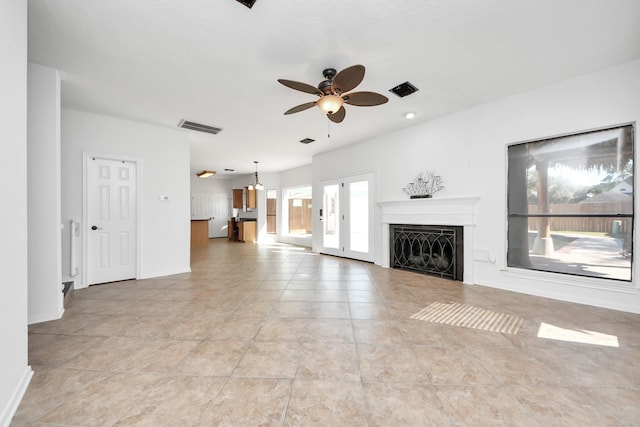 unfurnished living room with ceiling fan, light tile patterned flooring, a fireplace, visible vents, and baseboards