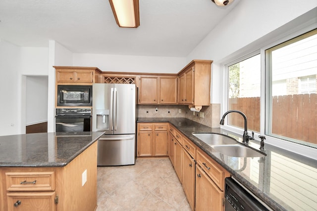 kitchen featuring light tile patterned floors, tasteful backsplash, dark stone countertops, black appliances, and a sink