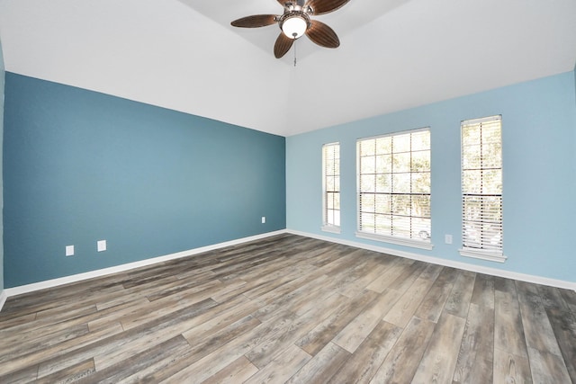 spare room featuring vaulted ceiling, wood finished floors, a ceiling fan, and baseboards