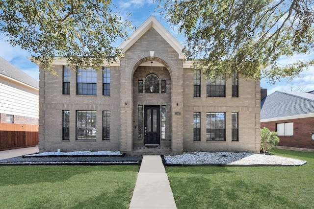 view of front facade with fence, a front lawn, and brick siding