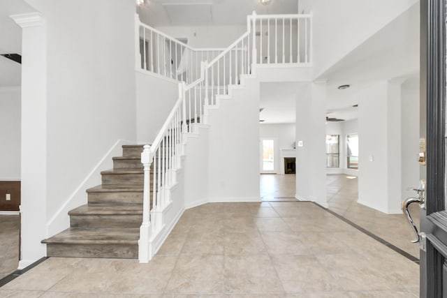 foyer featuring baseboards, a fireplace, and a high ceiling