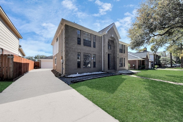 colonial home featuring brick siding, a front yard, fence, a garage, and an outdoor structure