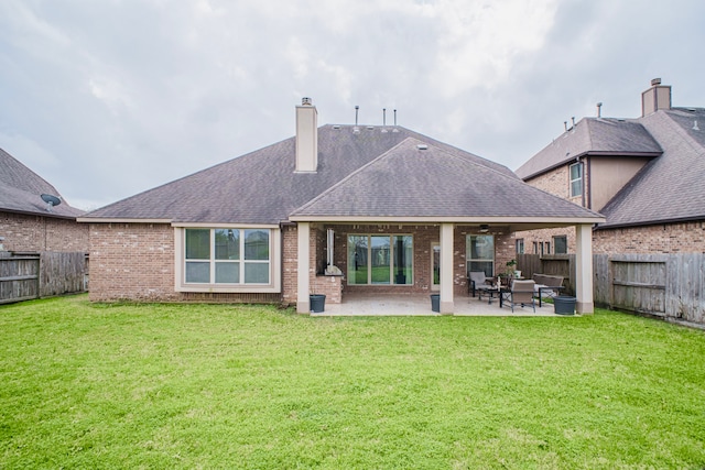 back of house with a fenced backyard, a chimney, a yard, a patio area, and brick siding