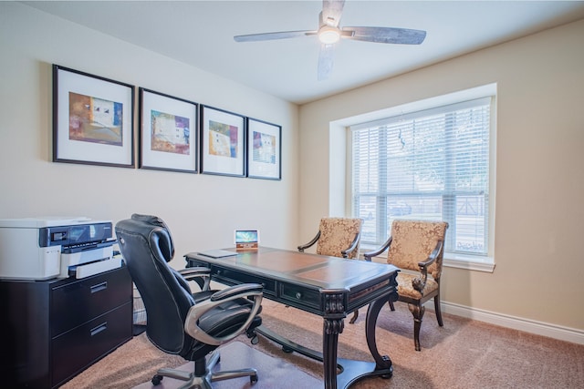 office area featuring light carpet, a ceiling fan, and baseboards