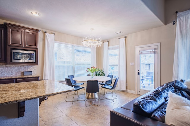 dining room with a healthy amount of sunlight, an inviting chandelier, visible vents, and light tile patterned flooring