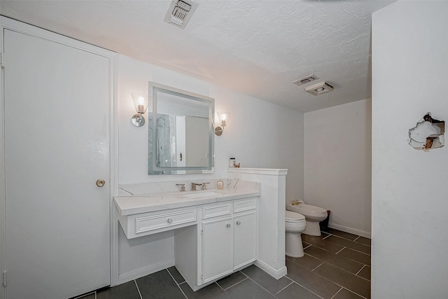 bathroom featuring visible vents, toilet, a bidet, a textured ceiling, and vanity