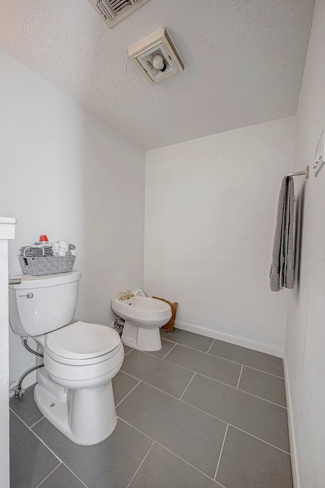 half bath featuring visible vents, toilet, tile patterned floors, a textured ceiling, and a bidet