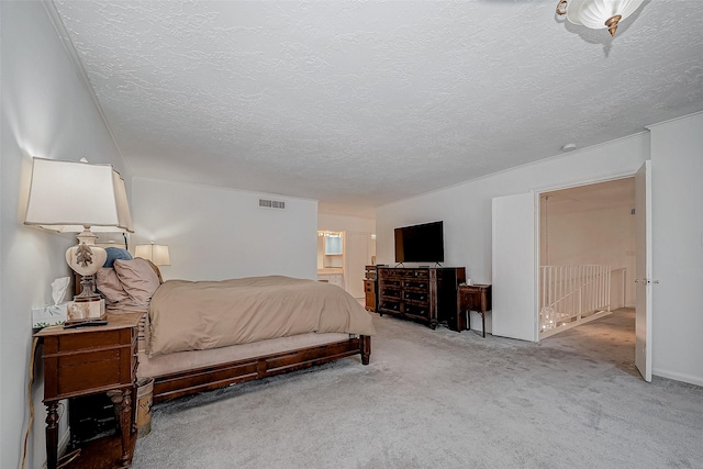 bedroom featuring a textured ceiling, ensuite bath, visible vents, and light colored carpet