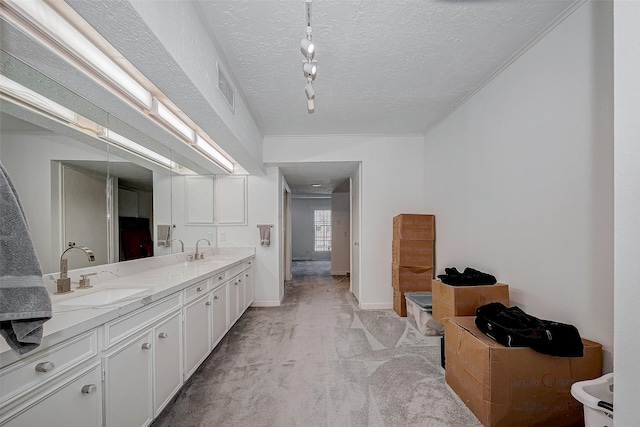 bathroom featuring a textured ceiling, double vanity, a sink, and visible vents