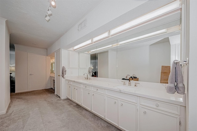 full bath with visible vents, a sink, a textured ceiling, and double vanity