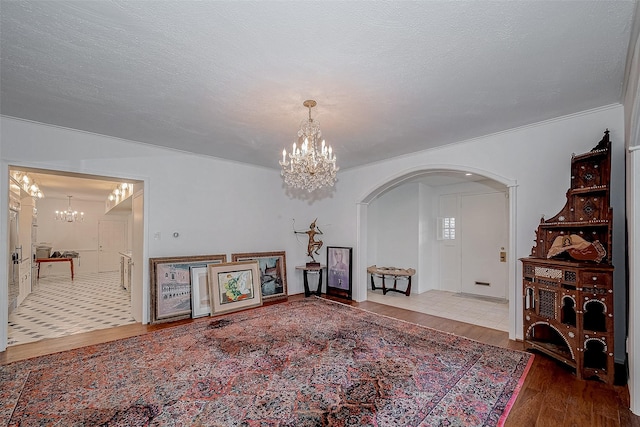 living area featuring a textured ceiling, arched walkways, wood finished floors, and an inviting chandelier