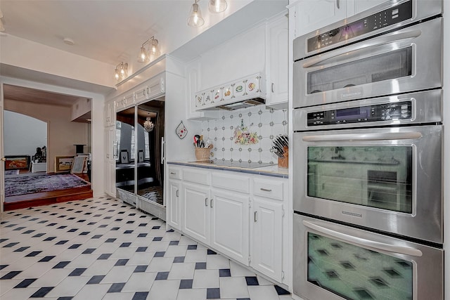 kitchen with light countertops, decorative backsplash, stainless steel double oven, white cabinets, and black electric cooktop