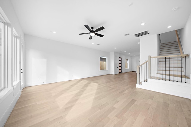 unfurnished living room featuring light wood-style floors, visible vents, stairway, and recessed lighting