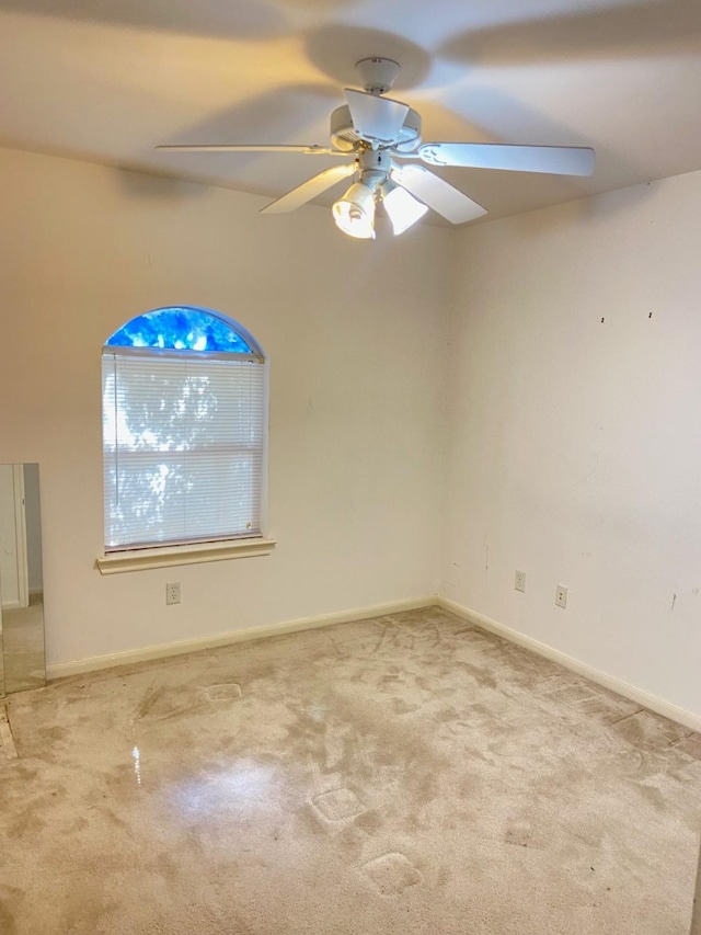 empty room featuring ceiling fan, baseboards, and light colored carpet