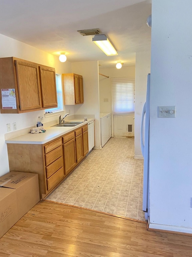 kitchen with brown cabinets, light wood-type flooring, light countertops, and a sink