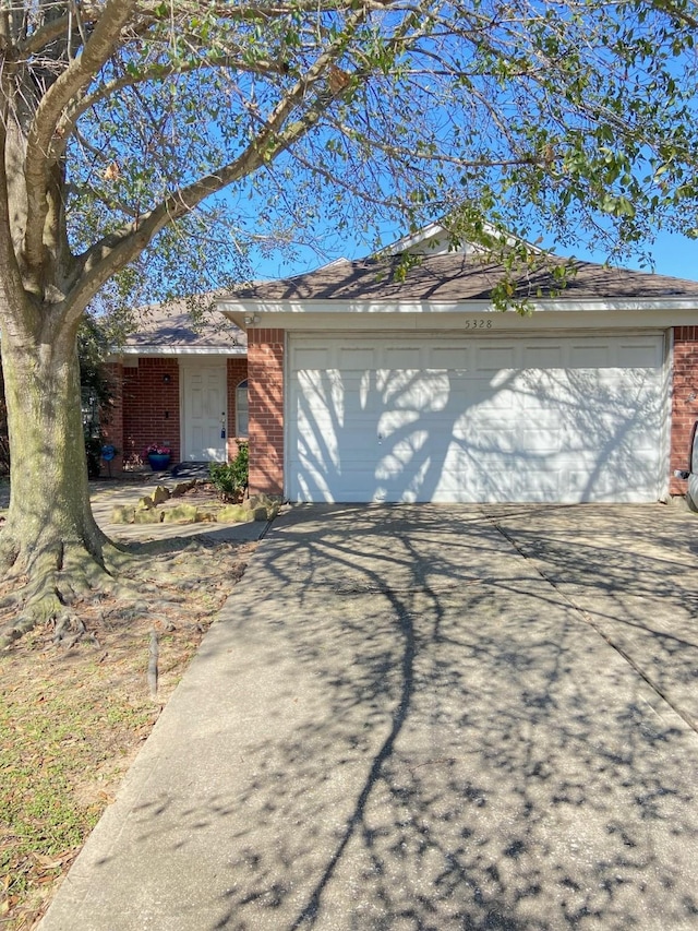 ranch-style house featuring an attached garage, driveway, and brick siding