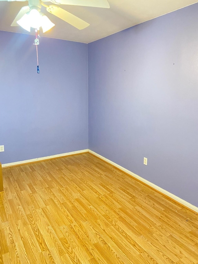 spare room with light wood-type flooring, a ceiling fan, and baseboards