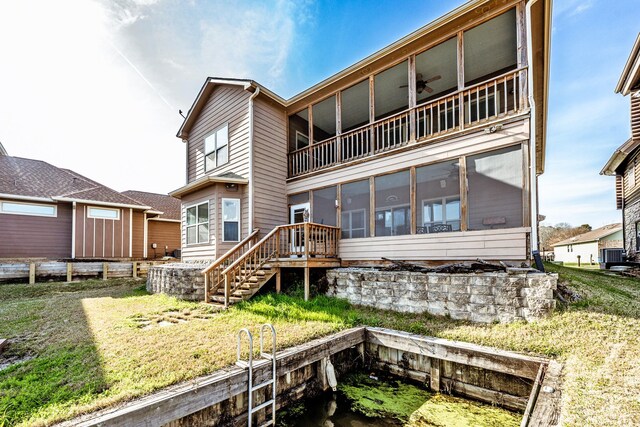 rear view of property featuring a lawn, central AC unit, a ceiling fan, a sunroom, and stairs