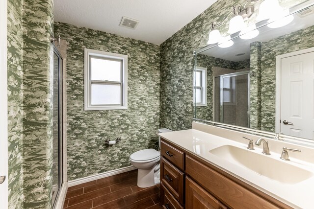 bathroom with toilet, wood finish floors, visible vents, a shower stall, and wallpapered walls