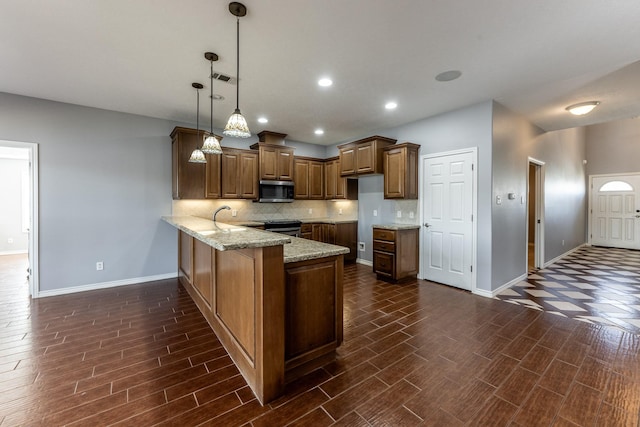 kitchen featuring appliances with stainless steel finishes, brown cabinets, a peninsula, pendant lighting, and backsplash