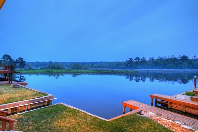 view of dock with a lawn and a water view