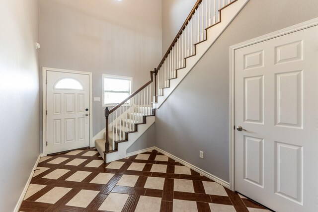 entrance foyer featuring stairway, a towering ceiling, and baseboards