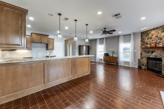 kitchen featuring open floor plan, light stone counters, visible vents, and pendant lighting