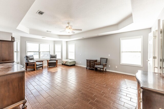 sitting room with baseboards, visible vents, wood tiled floor, a tray ceiling, and a textured ceiling