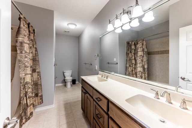 bathroom with toilet, tile patterned flooring, double vanity, and a sink