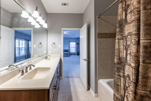 ensuite bathroom with tiled shower / bath, double vanity, a sink, and visible vents